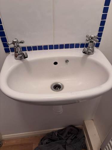 Small bathroom sink with cross-head taps and tiled splashback