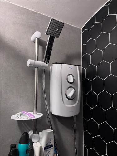 Electric shower installed with black hexagon wall tiles