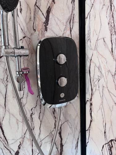 Modern electric shower installed on marble-effect tiles