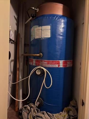 Hot water cylinder installation in an airing cupboard